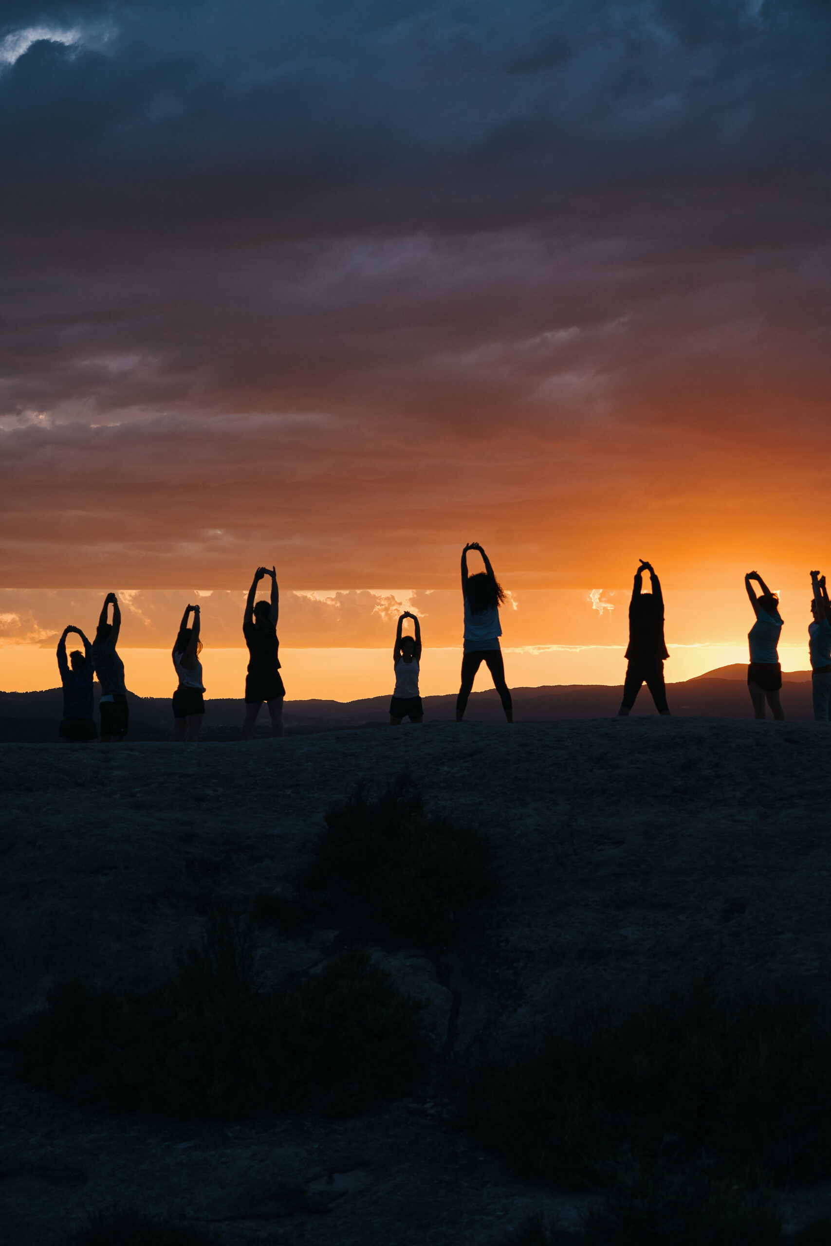 group people practicing yoga desert sunset